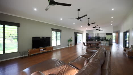 Luxury-lived-in-home-with-large-loungeroom-and-open-air-kitchen,-row-of-ceiling-fans-circulate-cool-air