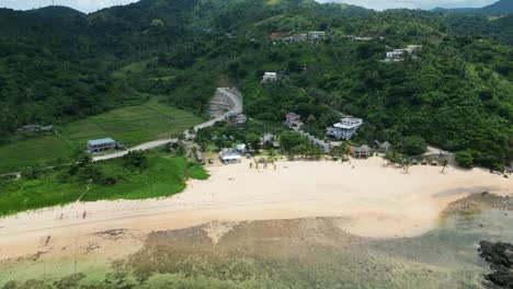 Aerial-orbit-of-idyllic-white-sand-beach-resort-with-lush-jungle-mountains-in-a-tropical-island-paradise