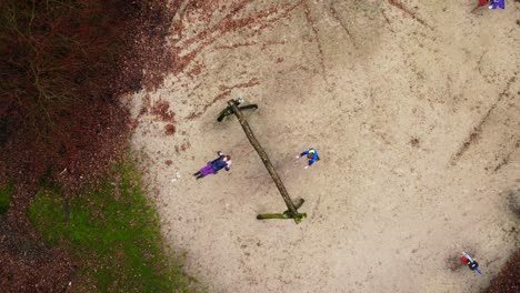 Top-down-view-on-children-swinging-and-wobbling-on-a-swing-in-a-playground