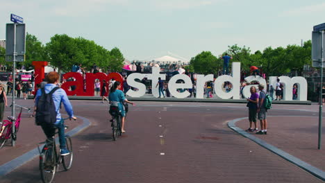 Famous-I-Amsterdam-sign-with-cyclist-and-tourists-walking-around,-giant-letters