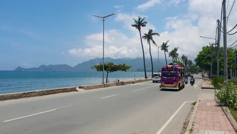 Scenic-ocean-view-on-waterfront-street-with-colorful-pink-modified-bus-in-the-capital-city-of-East-Timor-and-traveling-into-the-districts-with-passengers