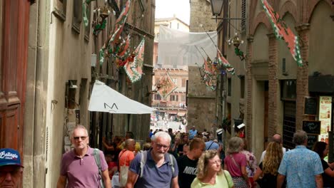 People-walking-down-a-Sienna-street-at-The-Suckling-Pig-Festival-Of-Monte-San-Savino