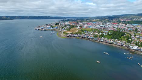 Castro-island's-coastline-with-boats-and-stilt-houses,-aerial-view