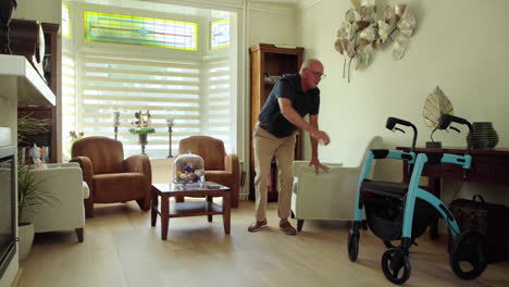 Retired-elderly-man-in-living-room-gets-up-from-armchair-to-grab-mobility-aid