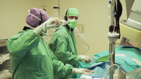 Two-doctors-in-operation-room-placing-a-stent-in-patients-body,-hospital-scene
