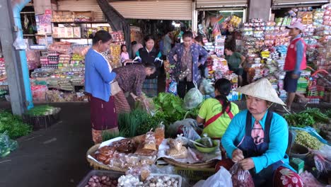 A-public-market-is-bustling-with-activity-as-individuals-tend-to-their-product-displays,-shoppers-make-purchases,-and-pedestrians-move-about