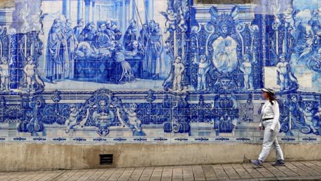 Woman-walking-in-front-of-the-tiled-wall-of-Chapel-of-the-Souls,-Porto