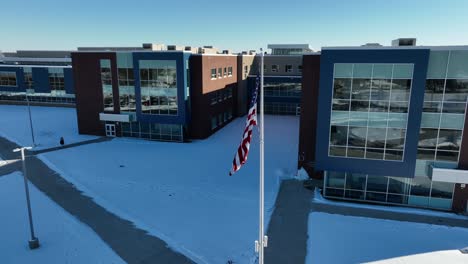 Aerial-establishing-shot-of-an-American-flag-in-front-of-a-school-building