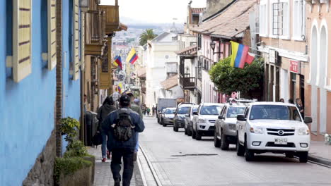 Kolumbiens-Straße-Mit-Flaggen-In-Bogota,-Die-Innenstadt-Im-Hintergrund-Sichtbar,-Menschen-Gehen-In-Zeitlupe-Nach-Unten