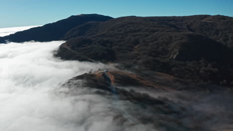 Neblige-Hügel,-Bedeckt-Von-Einer-Wolkendecke-Mit-Einem-Klaren-Blauen-Himmel-Darüber,-Luftaufnahme
