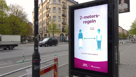 Covid-Virus-Informationen-Auf-Einem-Digitalen-Straßenschild-In-Stockholm,-Verkehr-Im-Hintergrund