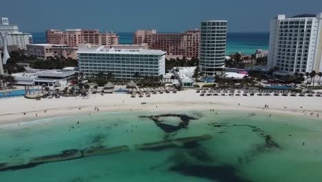 Cancun-beachfront-with-clear-turquoise-waters-and-bustling-shoreline,-aerial-view