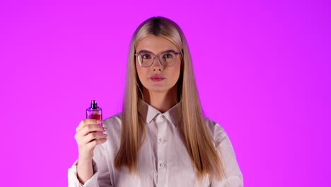 Caucasian-smart-looking-woman-opens-up-a-perfume-smelling-and-trying-fragrances-in-chroma-background-infinite-pink-isolated-portrait-female-shot