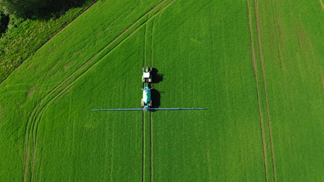 Farmer-in-tractor-spraying-fertilizer-on-green-field