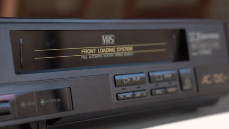 Einlegen-Einer-VHS-Videokassette-Und-Drücken-Der-Wiedergabetaste-Auf-Einem-Vintage-Player-Aus-Den-1980er-Jahren,-Nahaufnahme