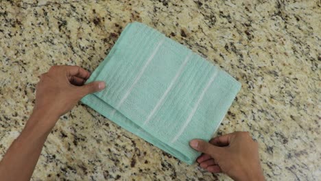 Folding-green-towel-on-marble-table,-top-down-view