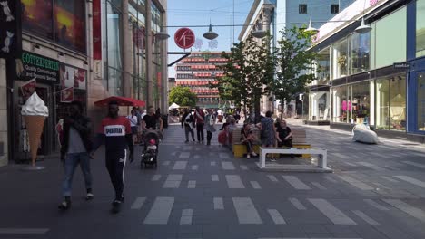 People-walk-on-Sergelgatan-in-central-Stockholm,-Sweden,-on-a-summer-day