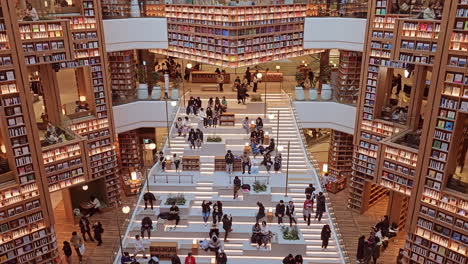 Innenansicht-Der-Starfield-Bibliothek-In-Suwon-Mit-Entspannten-Menschen-Auf-Zentralen-Treppenbänken,-Umgeben-Von-Hoch-Aufragenden-Bücherregalwänden---Draufsicht