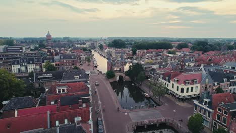 A-european-town-at-dusk-with-historic-buildings-along-a-calm-canal,-soft-lighting,-aerial-view