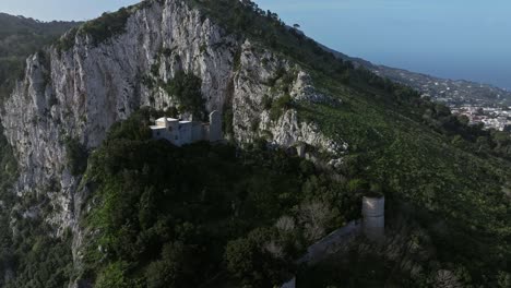 Toma-Aérea-De-Una-Solitaria-Casa-Blanca-En-Lo-Alto-De-Escarpados-Acantilados-De-Capri-Con-Vistas-Al-Mar.