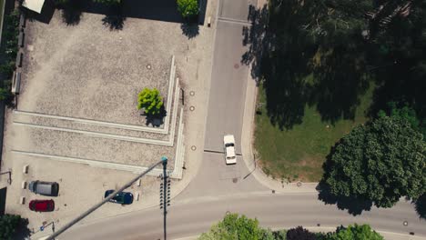A-car-driving-through-a-quiet-suburban-neighborhood,-trees-casting-shadows,-aerial-view