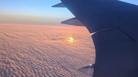 Die-Tragfläche-Eines-Jets-über-Der-Orangefarbenen-Wolkendecke-Bei-Sonnenaufgang
