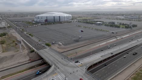 State-Farm-Stadium,-Heimstadion-Der-National-Football-Mannschaft-Der-Arizona-Cardinals-In-Glendale,-Arizona,-Mit-Weitwinkelaufnahme-Einer-Drohne-Von-Der-Autobahn,-Die-Sich-Im-Kreis-Bewegt