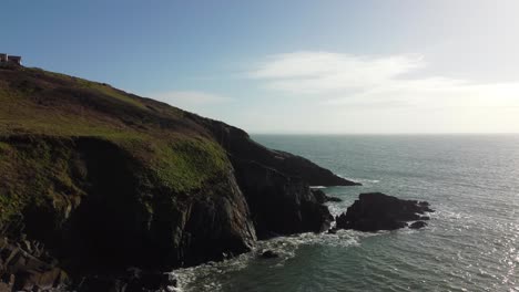 Retreating-Drone-Shot-of-Welsh-Coastline-with-House-on-Top-of-Hill