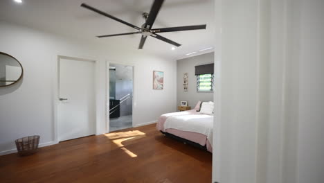 Establishing-reveal-of-large-open-bedroom-with-beautiful-natural-lighting-and-ceiling-fan