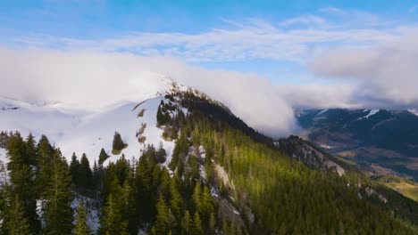 Flying-over-mountain-valley-with-snow-and-pines-and-strange-falling-clouds