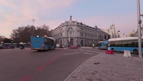 Establishing-shot-Sunrise-Madrid-Banco-de-Espana-Bank-of-spain-in-Cibeles-square-with-colorful-beautiful-clouds-and-rush-hour-city-morning-traffic