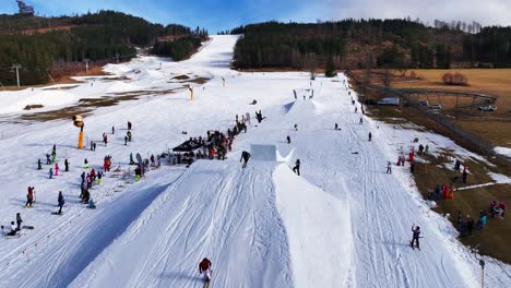 Skiers-and-snowboarders-jump-on-ramp-and-perform-tricks,-Dolni-Morava