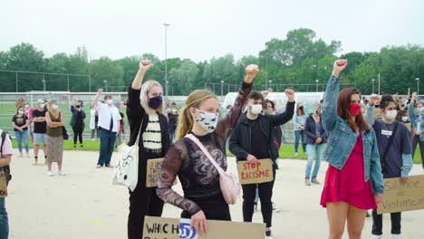 Zoom-in-on-blond-girl-during-Black-Lives-Matter-protest-in-The-Netherlands,-teenagers-holding-fist-up,-solidarity