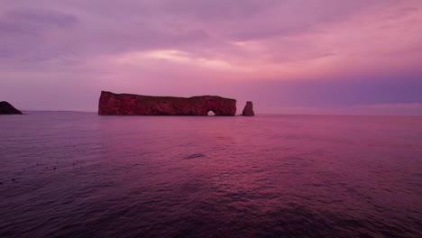 Drone-view-receding-from-Percé-Rock-during-a-cloudy-sunset