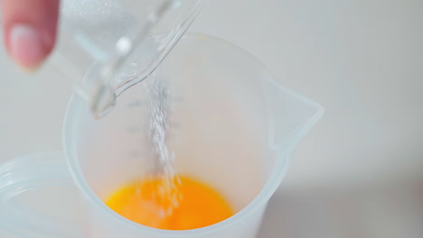 Hand-Sprinkling-Sugar-into-Egg-Yolk-Liquid-for-Sweet-Culinary-Creation
