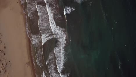 Top-down-shot-of-peaceful-beach-with-lapping-ocean-waves