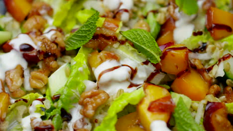 Close-up-of-healthy-salad,-nectarine-and-walnut-lunch-plate-spinning-in-close-up