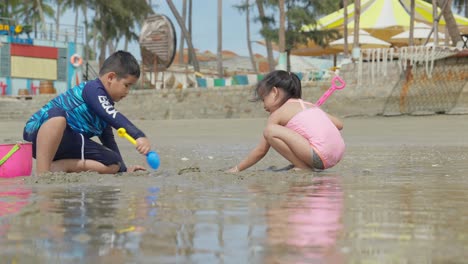 Dos-Niños-Asiáticos-Jugando-En-La-Arena-De-Una-Hermosa-Playa