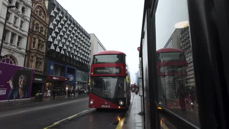Rainy-day-on-Oxford-Street-in-London-with-red-double-decker-bus,-wet-urban-scene,-reflections-on-window