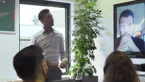 Leader-of-the-group-pointing-at-screen-during-video-conference,-corporate-office-meeting