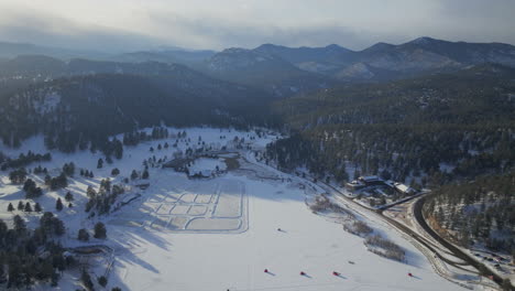 Sunset-Ice-skating-skate-hockey-rink-lake-pond-hockey-winter-Etown-Evergreen-Lake-house-fishing-tents-Denver-golf-course-Colorado-aerial-cinematic-drone-golden-hour-winter-snow-traffic-backward-motion