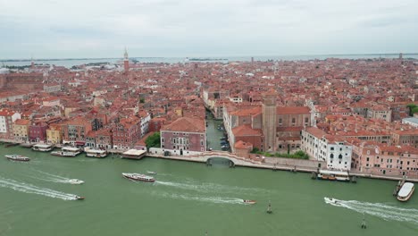 Venice's-iconic-red-roofs-and-canals-with-boats,-on-a-cloudy-day,-aerial-view