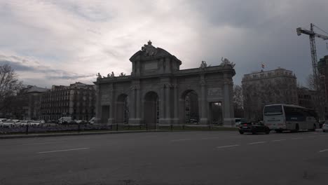 Toma-Estabilizada-De-La-Puerta-De-Alcalá-En-Madrid,-España,-En-Una-Puesta-De-Sol-Nublada.