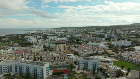 This-aerial-shot-showcases-Protaras,-a-Cypriot-seaside-town-known-for-its-array-of-white-and-blue-buildings,-indicative-of-Mediterranean-resorts