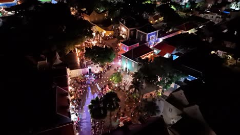 Panoramic-aerial-tilt-down-to-Kura-Hulanda-village-in-Otrobanda-Willemstad-Curacao-at-night-with-string-lights