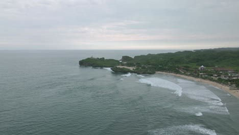 Drone-fly-over-wavy-beach-with-green-vegetation