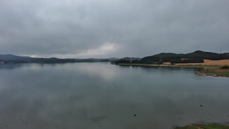 Overcast-day-at-Nanclares-de-Gamboa,-tranquil-waters-and-green-shores,-Basque-Country,-Spain