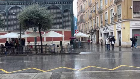 People-with-umbrellas-crossing-the-street,-vibrant-city-life-despite-the-rain