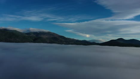 Vuelo-De-Drones-Sobre-Las-Nubes-Visualizando-Las-Montañas-Más-Altas-Dejando-Un-Mar-De-Nubes-Como-Suelo-Con-Un-Cielo-Azul-Con-Nubes-Altas-En-La-Mañana-En-Invierno-En-Un-Valle-En-ávila-España