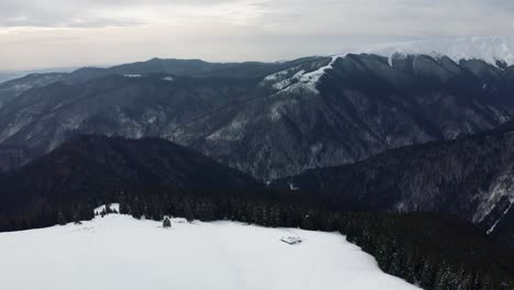 Snow-covered-Rausor-Dam-in-Iezer-Papusa-Mountains,-Arges,-Romania,-captured-from-aerial-view-in-winter